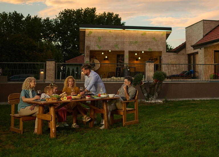 Family enjoying dinner at sunset in backyard